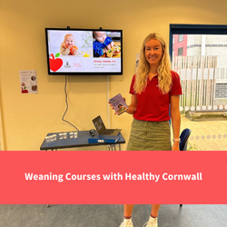 healthy cornwall staff member smiles at camera while delivering a course next to screen saying Ready steady Eat, text reads "Weaning courses with healthy cornwall"