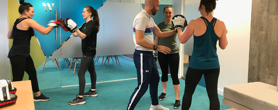 Man teaching women in a workplace to do boxercise